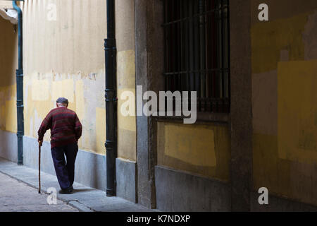 Vieil homme avec quelques malades et wearing cap flâner dans la vieille ville d'Avila, Espagne Banque D'Images