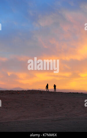 Deux personnes bénéficiant d'un beau coucher du soleil dans la Valle de la Luna (vallée de la Lune) dans la région d'Atacama au nord du Chili Banque D'Images