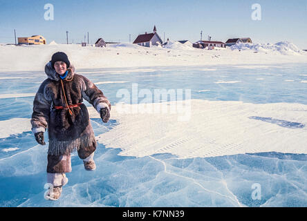 Visiteur vêtu de vêtements traditionnels en peau de caribou et de bottes, de marcher à travers la glace à Baker Lake, Nunavut, Canada. Banque D'Images
