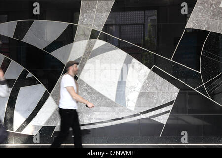 Un homme marche en avant du mur carrelé art dans la gare centrale d'Oslo, Norvège Banque D'Images