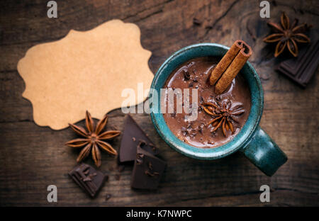 Dans une tasse de chocolat chaud avec un bâton de cannelle, l'étoile d'anis et de chocolat noir sur fond de flocons en bois rustique avec une balise vide. Vue aérienne avec c Banque D'Images