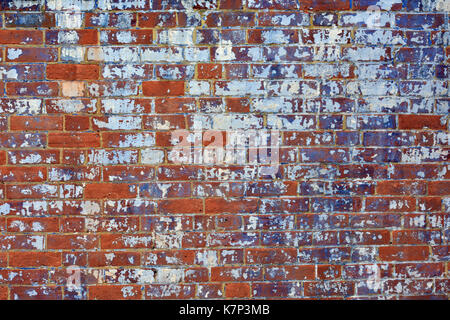 Un mur de brique avec fading peindre en mauve et blanc montrant des signes d'usure et de re-décoration. Un mur de brique rouge de style édouardien victorienne ou la maçonnerie. Banque D'Images