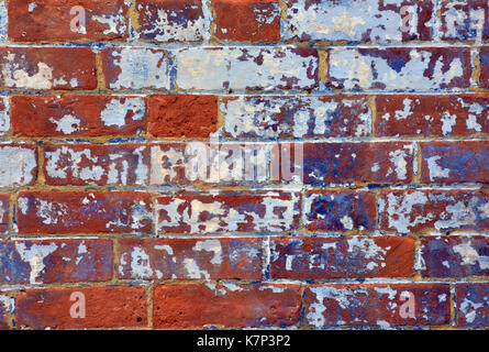 Un mur de brique avec fading peindre en mauve et blanc montrant des signes d'usure et de re-décoration. Un mur de brique rouge de style édouardien victorienne ou la maçonnerie. Banque D'Images