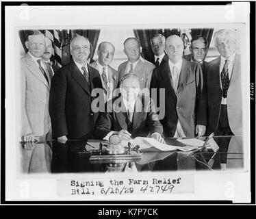 Le président Herbert Hoover (assis, au centre) signe le projet de loi de secours agricole, entouré par les dirigeants du Congrès y compris Nicholas Longworth, Président de la Chambre des Représentants, à gauche de Hoover, Washington, DC, 06/15/1929. Banque D'Images