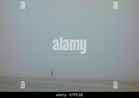 Une personne qui marche sur une plage dans le brouillard Banque D'Images