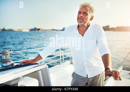 Couple sur le pont d'un bateau naviguant le long de la côte sur une journée ensoleillée Banque D'Images