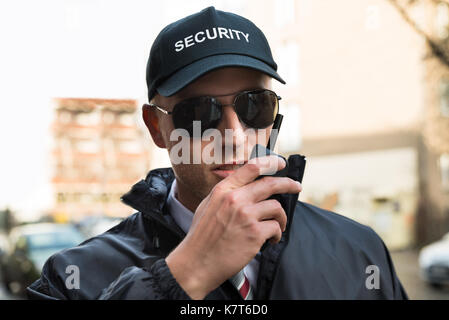 Portrait de jeune homme gardien de sécurité en conversation sur talkie walkie Banque D'Images