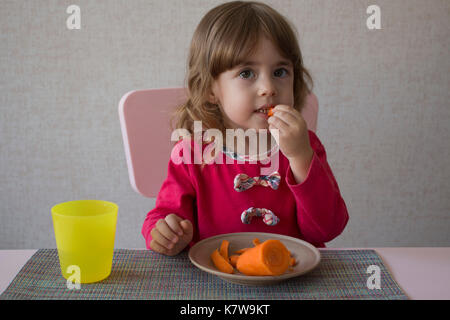 Cute little girl eats carotte Banque D'Images