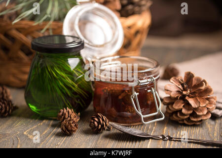 Un pot de confiture maison faite de cônes de pin et de cèdre du miel sur un fond de bois foncé. macro. Banque D'Images