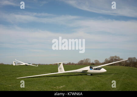 Deux planeurs au sol avec un troisième planeur remorqué dans l'air par un avion de remorquage. Storrington, West Sussex, Royaume-Uni Banque D'Images