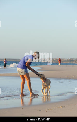Jeune femme joue avec son Golden Retriever sur la plage Banque D'Images