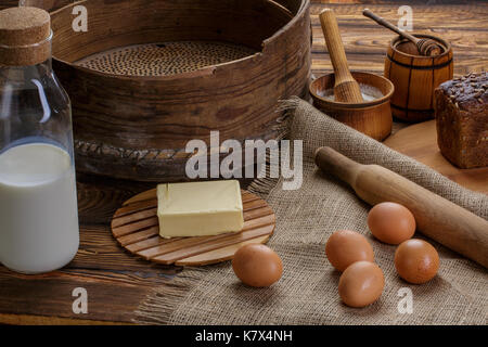 Produits biologiques : oeufs, lait, pain, beurre, le blé sur un fond de bois et de la toile de jute Banque D'Images