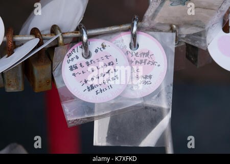 Petit rond blanc et rose cartes de correspondance, attaché aux verrous, avec coeur rose au centre avec l'écriture japonaise pour le souhaite, bonne chance et l'amour. Banque D'Images