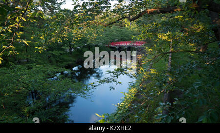 Vue sur le pont japonais rouge traditionnel sur moat en été les touristes d'arbres reliant château d'Hirosaki dans la préfecture d'Aomori, au Japon. Banque D'Images