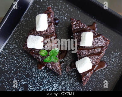 Délicieux gâteau au chocolat avec une lame et des pièces découpées sur fond de bois. Banque D'Images