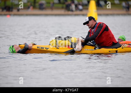 Nager dans l'épreuve de natation de Serpentine la Serpentine, à Hyde Park, Londres. Un canoéiste sécurité aide un nageur avec crampe. Banque D'Images