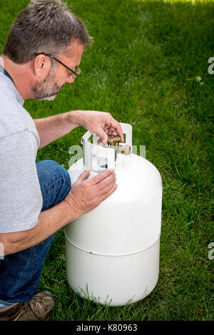 Personne qui travaille sur le bouton de fermeture d'un réservoir de propane Banque D'Images