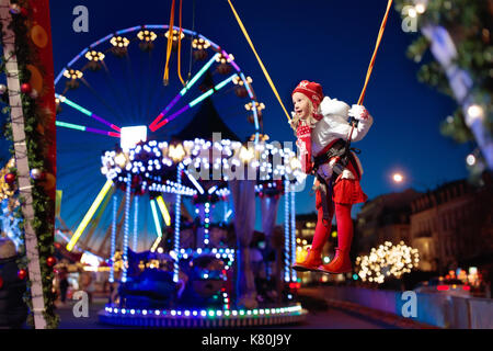 Enfant à Noël juste amusement. petite fille à saut park. kids aller au marché de Noël au centre-ville sur soirée froide. les enfants outd Banque D'Images