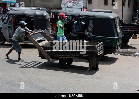 Un homme poussant sa brouette le long d'une rue très fréquentée dans le quartier de pettah de Colombo, Sri Lanka Banque D'Images