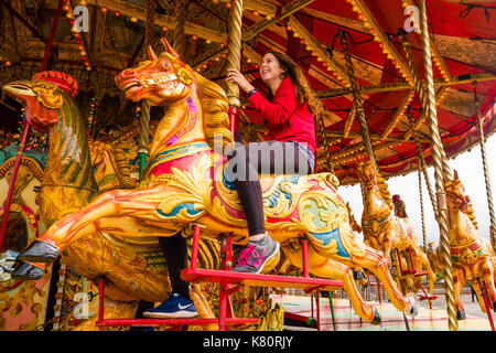 Pays de Galles Aberystwyth uk, dimanche 17 septembre 2017 une jeune femme bénéficiant d'un trajet sur l'noyce & sons célèbre 'golden gallopers ornés' fairground attraction carrousel pendant un week-end d'événements pour célébrer 95 ans de la great western sur la vallée de chemin de fer à voie étroite de rheidol à Aberystwyth Photo © Keith morris / alamy live news Banque D'Images