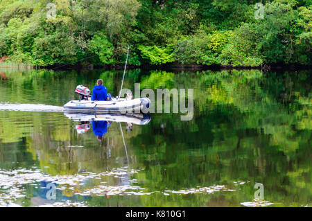 Loch Ard, Ecosse, Royaume-Uni. 17 Septembre, 2017. Météo France : Un homme d'un petit bateau de pêche avec son chien, la journée calme offre des réflexions sur la surface de l'eau. Loch Ard est un organe de l'eau douce dans le parc national du Loch Lomond et des Trossachs du district de Stirling en Écosse. Credit : Skully/Alamy Live News Banque D'Images