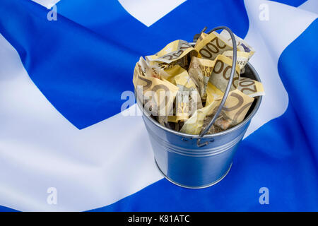 Drapeau grec avec un seau en métal de 200 billets en euros. Pour la crise financière grecque et le sauvetage, l'allégement de la dette grecque, la crise économique grecque, la récession grecque. Banque D'Images