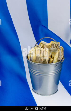 Drapeau grec avec un seau en métal de 200 billets en euros. Pour la crise financière grecque et le sauvetage, l'allégement de la dette grecque, la crise économique grecque, la récession grecque. Banque D'Images