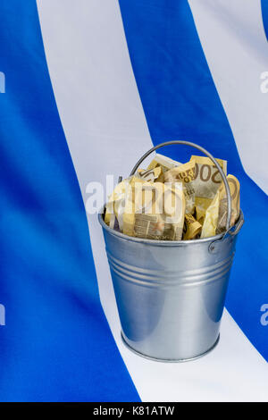 Drapeau grec avec un seau en métal de 200 billets en euros. Pour la crise financière grecque et le sauvetage, l'allégement de la dette grecque, la crise économique grecque, la récession grecque. Banque D'Images