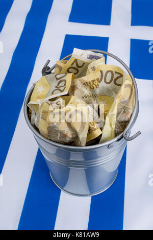 Drapeau grec avec un seau en métal de 200 billets en euros. Pour la crise financière grecque et le sauvetage, l'allégement de la dette grecque, la crise économique grecque, la récession grecque. Banque D'Images