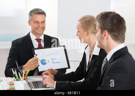 Mature businessman expliquant graphique pour ses collègues in office Banque D'Images