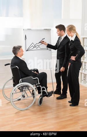 Businesspeople écoute attentivement young businessman expliquant le graphique sur tableau blanc Banque D'Images