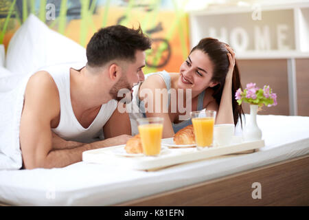 Smiling couple ont un petit-déjeuner romantique au lit Banque D'Images