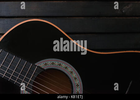 Corps de guitare acoustique noir, gros plan sur une table en bois noir, l'arrière-plan avec beaucoup de texture, montrant la forme de guitare Banque D'Images