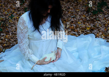 Young girl holding a white rat dans une robe blanche Banque D'Images