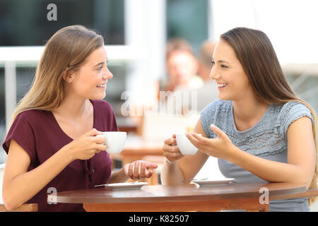 Deux amis heureux d'avoir une bonne conversation assis dans un bar terrasse Banque D'Images