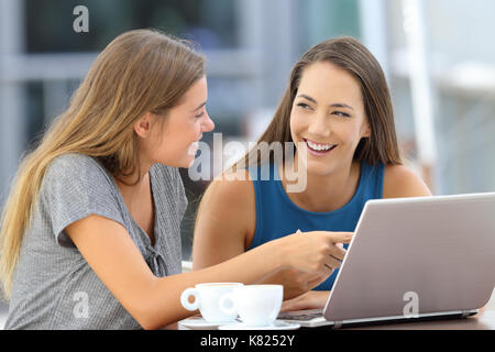 Deux amis heureux de parler de contenu en ligne assis dans un bar terrasse Banque D'Images