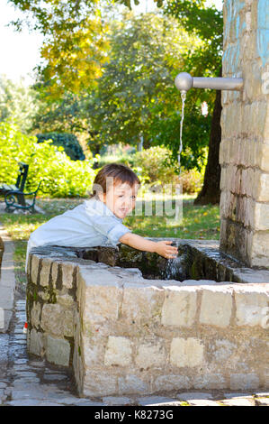 Happy boy lave-mains dans un parc Banque D'Images