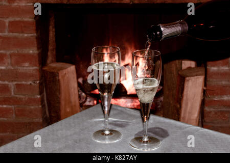 Deux verres de champagne en face de la cheminée à bois pour célébrer une soirée romantique avec sweetheart Banque D'Images
