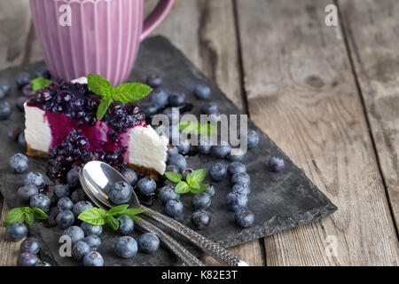 Morceau de gâteau au fromage fait maison avec de la confiture de bleuets et de bleuets frais mûrs.copie espace arrière-plan. Banque D'Images