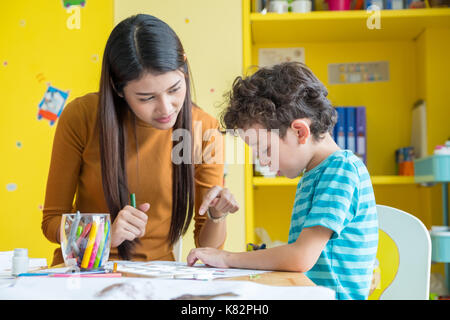 Asian woman teacher teaching boy kid de couleur peinture livre sur table en classe de maternelle de l'école éducation,. Banque D'Images