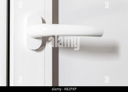 Poignée en plastique blanc d'une porte blanche close-up. Banque D'Images