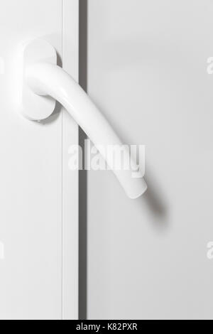 Poignée en plastique blanc d'une porte blanche close-up. Banque D'Images