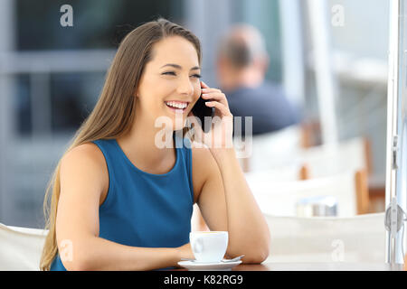Seul woman having a phone conversation assis dans un bar terrasse Banque D'Images