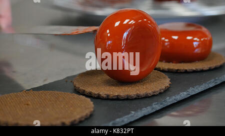 Femme chef expose un gâteau sur une assiette de présentation, dessert dessert cookies décorés. Banque D'Images