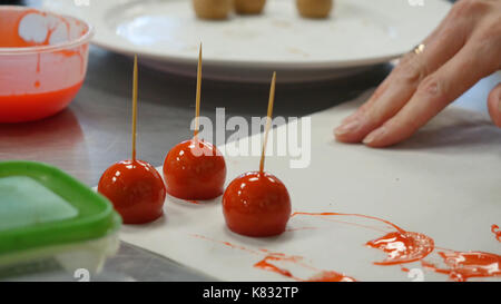 Femme trempant candy apple dans le bol avec le caramel. Banque D'Images