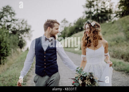 Belle mariée et le marié dans la nature verte, se tenant la main. Banque D'Images