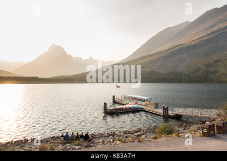 Regardez les swiftcurrent lake, de nombreux parc national des glaciers avec le chef historique deux fusils bateau amarré à la rampe de mise à l'swiftcurrent lodge Banque D'Images