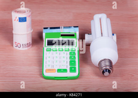 Basse consommation avec la calculatrice et de l'argent sur fond de bois. Banque D'Images