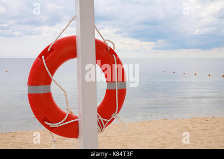 Anneau de vie accroché à un pilier, sur la plage contre la mer Banque D'Images