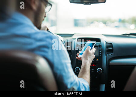 L'homme à l'aide de téléphone en conduisant la voiture Banque D'Images